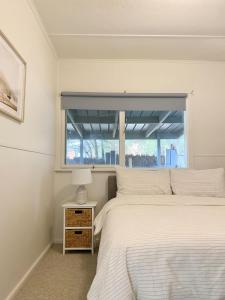 a bedroom with a white bed and a window at Sunny Coastal Retreat in Anglesea +10 photos
