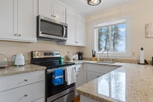 a kitchen with white cabinets and a black stove top oven at Tranquility Bay Getaway by Simple Life Rentals in Sister Bay