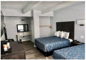 a hotel room with two beds and a television at Sea Garden Inn Pismo Beach- San Luis Obispo in Pismo Beach
