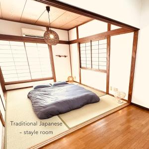a bedroom with a bed in a room with windows at Between Kyoto & Osaka 渚南 駅徒歩3分 in Hirakata