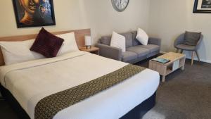 a hotel room with a bed and a couch at Tudor Lodge Motel in Nelson