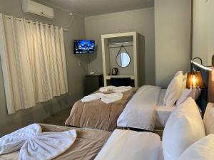 a room with two beds and a television in it at Pousada HG -101-Suíte in Vila Nova do Sul