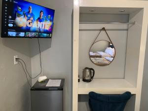 a room with a tv on the wall and a refrigerator at Pousada HG -101-Suíte in Vila Nova do Sul
