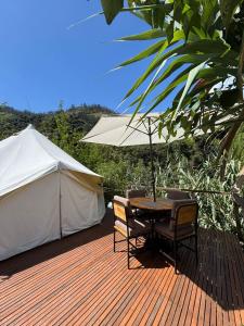 a wooden deck with a table and chairs and a tent at QuillaGlamping in Píllaro