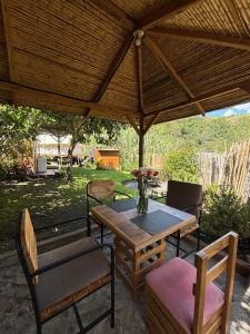 a wooden table and chairs under a wooden umbrella at QuillaGlamping in Píllaro