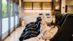 a woman sitting in a chair taking a picture with her cell phone at The Bridge Hotel Shinsaibashi in Osaka