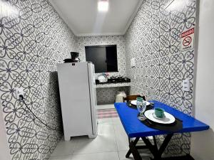 a kitchen with a refrigerator and a table with a blue table at Âncora Lofts in Arraial do Cabo