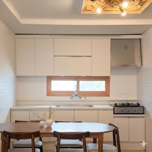 a kitchen with white cabinets and a table and chairs at sinae stayG in Seoul