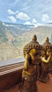 two statues sitting on a table looking out a window at Ivory Nest Villa in Chamba