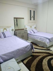 two beds in a white room with a mirror at Holiday apartment in ‘Izbat al Waqf