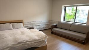a bedroom with a bed and a couch and a window at サンライズ日南 in Nichinan