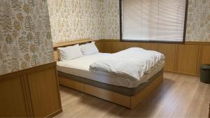 a bedroom with a bed with white sheets and a window at サンライズ日南 in Nichinan