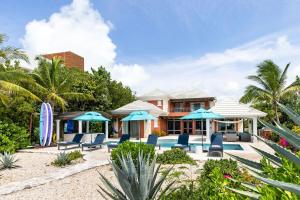 a house with a pool and chairs and umbrellas at Villa La Percha in Providenciales