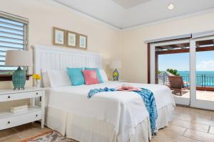 a white bedroom with a bed and a view of the ocean at Villa La Percha in Providenciales