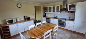 a kitchen with a wooden table and white cabinets at Sinilille 5 Holiday Home in Kuressaare