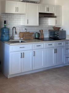 a kitchen with white cabinets and a sink and a microwave at Resort Casita in Playa Venao