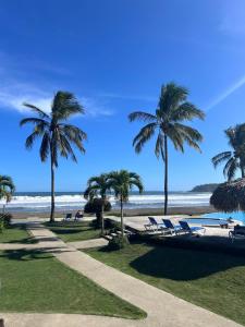 a beach with palm trees and chaise lounge chairs at Resort Casita in Playa Venao