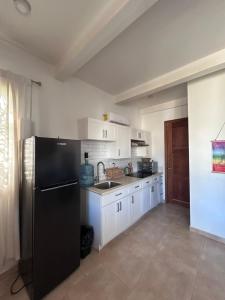 a kitchen with a black refrigerator and white cabinets at Resort Casita in Playa Venao