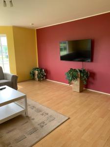 a living room with a red wall with a flat screen tv at Sinilille 5 Holiday Home in Kuressaare