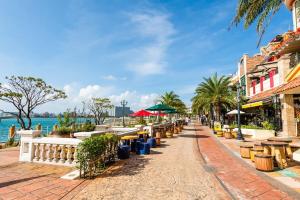 a street with tables and chairs next to the water at Rela More in Ginowan