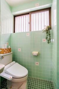a green tiled bathroom with a toilet and a sink at Rela More in Ginowan +72 photos