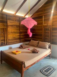 a bedroom with a bed with a pink umbrella at Thambili cabanas whisky point in Arugam Bay