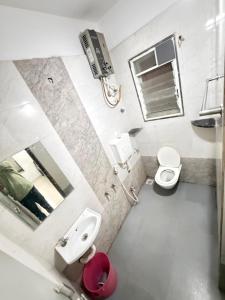 a bathroom with a sink and a toilet and a mirror at Gurukrupa Yatri Nivas in Kolhapur