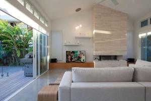a living room with a white couch and a fireplace at White Sands Beach House in Marcoola