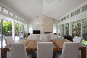 a dining room with a wooden table and white chairs at White Sands Beach House in Marcoola