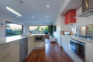 a kitchen with white cabinets and a large window at Green House in Marcoola