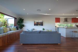 a living room with a blue couch and a kitchen at Green House in Marcoola
