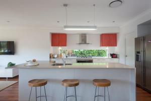 a kitchen with a large white island with two bar stools at Green House in Marcoola