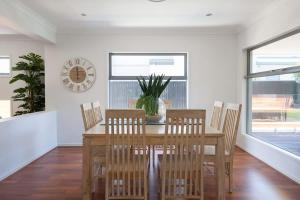 a dining room with a table and chairs and a clock at Green House in Marcoola