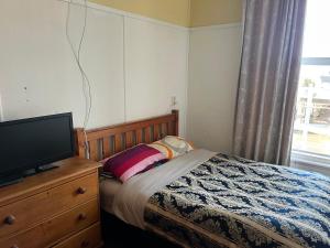 a bedroom with a bed and a television on a dresser at Sullivans backpackers in Waimate