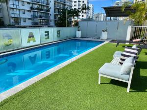 a swimming pool with two chairs and a table on a building at Mooloolaba Magic at Beachclub Mooloolaba in Mooloolaba
