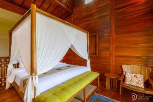 a bedroom with a canopy bed and a chair at Umah Dedari in Keramas +35 photos