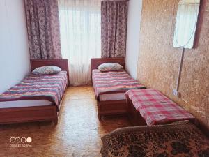 two twin beds in a room with a window at Коттедж Бурабай улица Алатау 38 in Borovoye