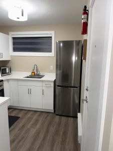 a kitchen with a stainless steel refrigerator and white cabinets at Modern Private Suite, Cozy, Stylish & Spacious in Regina +39 photos