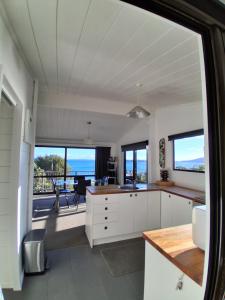 a kitchen with white cabinets and a view of the ocean at Island view Experience in Coromandel Town