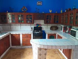a large kitchen with wooden cabinets and a blue wall at CASA MARCELa in Altagracia