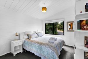 a white bedroom with a bed and a window at Island view Experience in Coromandel Town