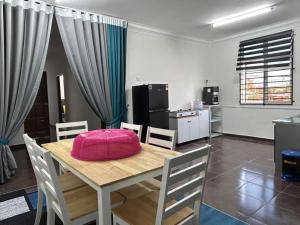 a dining room with a table with a pink pillow on it at Zinirah Homestay in Tumpat