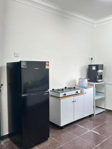 a kitchen with a black refrigerator and a stove at Zinirah Homestay in Tumpat