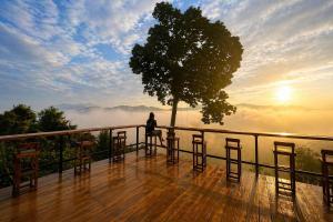 a person sitting on a deck with a tree at 4sky in Ban Kai Noi