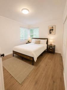 a bedroom with a bed with white sheets and wooden floors at Santorini Shores in Biscayne Park