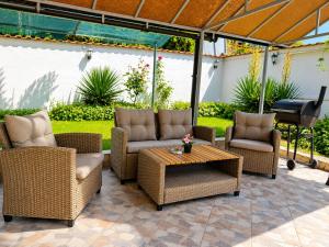 a patio with wicker chairs and a table and a grill at Guest House Orfey in Kranevo
