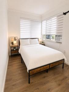 a bedroom with a large white bed and a window at Santorini Shores in Biscayne Park