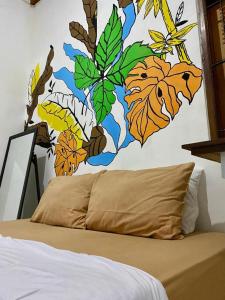 a bedroom with a painting of leaves on the wall at Zzz Ijen Hostel in Banyuwangi