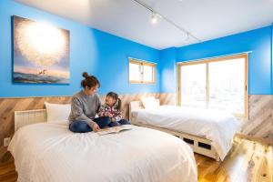 a woman and a child sitting on a bed at Hotel Beach-House in Otsu