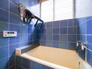 eine Badewanne in einem blau gefliesten Badezimmer in der Unterkunft E E House in Numazu